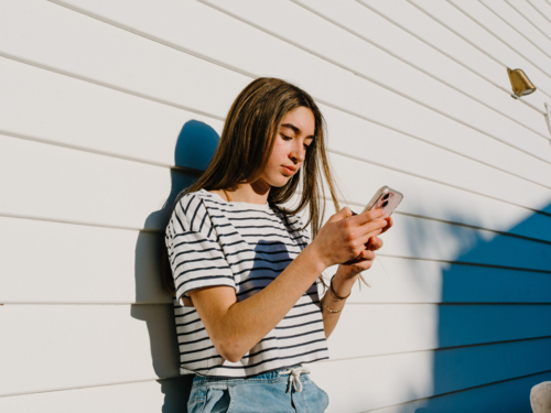 Young teenage girl holding a mobile device. - Australian Stock Image