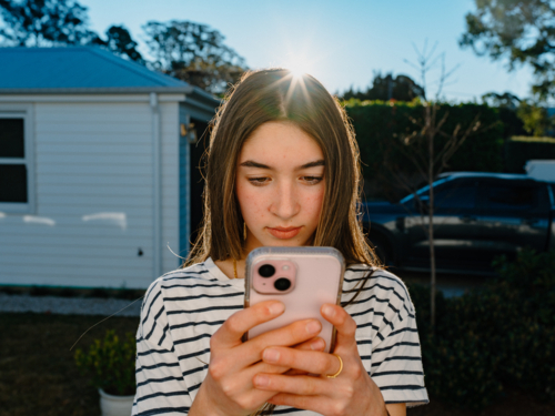 Young teenage girl holding a mobile device. - Australian Stock Image