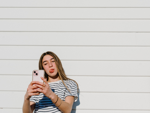 Young teenage girl taking selfies on a mobile device. - Australian Stock Image