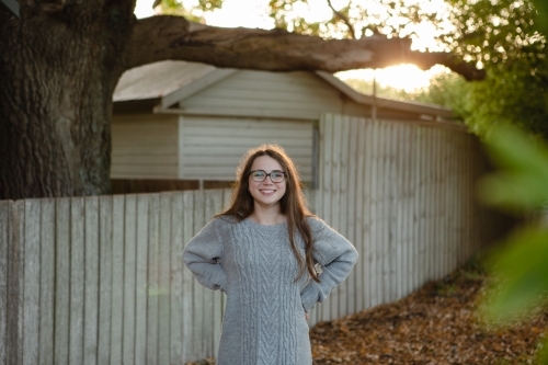 Young teenage girl with hands on hips smiling at camera - Australian Stock Image