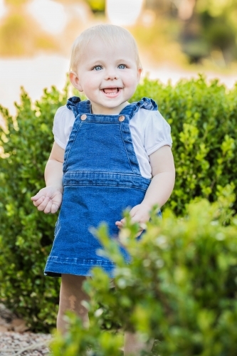 Young toddler girl with big smile playing in garden - Australian Stock Image