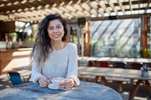 Young Turkish woman drinking coffee at cafe - Australian Stock Image