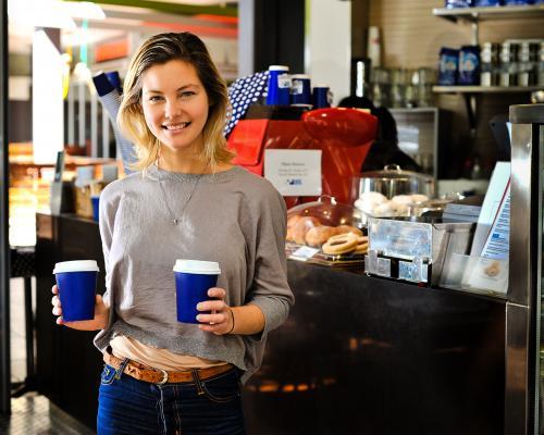 young woman buying takeaway coffees at a cafe - Australian Stock Image