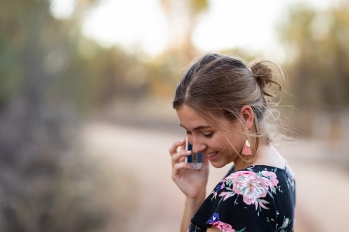young woman happily talking on phone outdoors with blurred background