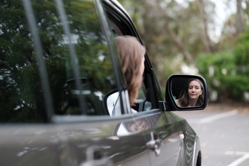 Young woman in 4wd vehicle looking in rear view mirror while parking - Australian Stock Image