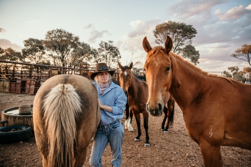 Young woman leaning on a horse in the yard - Australian Stock Image