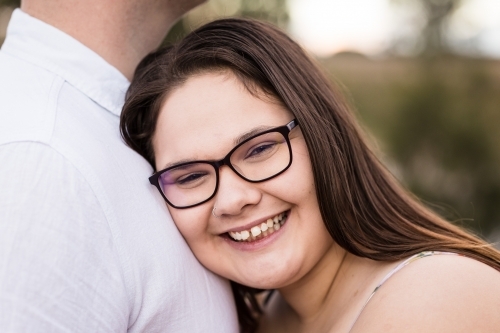Young woman leaning on boyfriend chest smiling - Australian Stock Image