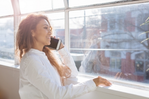 Young woman on a mobile phone with hazy backlighting - Australian Stock Image