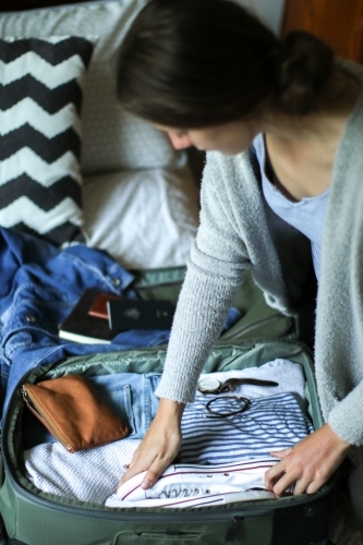 Young woman packing her bag ready to travel - Australian Stock Image