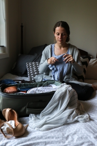 Young woman packing her bag ready to travel - Australian Stock Image