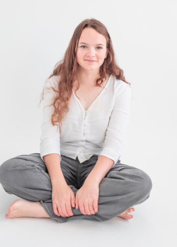 Young woman sitting cross-legged smiling - Australian Stock Image