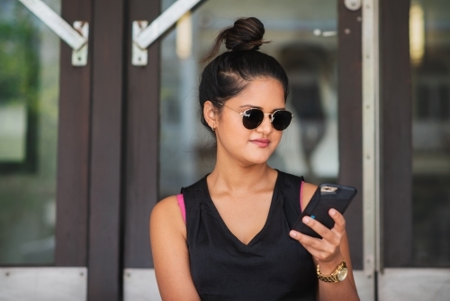 young woman sitting on stairs using phone - Australian Stock Image