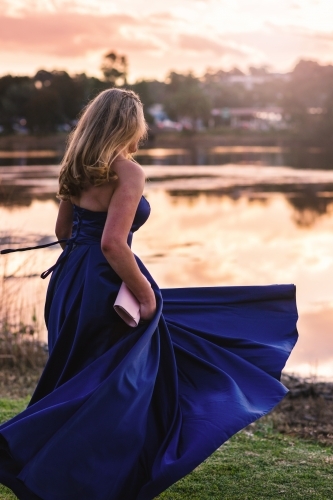 young woman spinning in formal dress in the afternoon light - Australian Stock Image