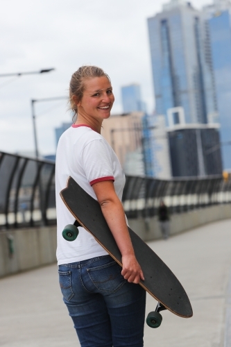 Young Woman Walking with Her Skateboard - Australian Stock Image