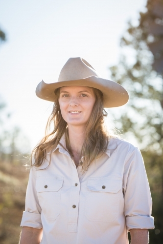 Young woman wearing akubra hat standing on family farm in drought - Australian Stock Image