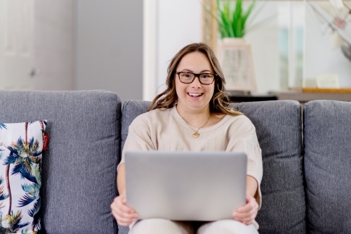 young woman with Down Syndrome using computer at home - Australian Stock Image