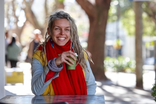 Young woman with dreadlocks smiling over coffee