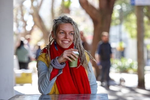 Young woman with dreadlocks smiling over coffee