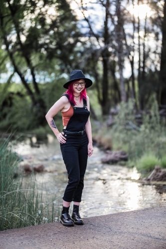 Young woman with pink hair standing near river water laughing - Australian Stock Image