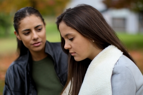 Young woman with upset expression being comforted by female partner